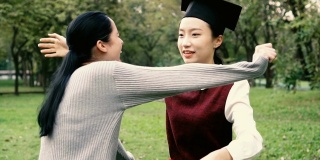年轻的亚洲女毕业生拥抱她的朋友在毕业典礼的慢镜头。国际多元化背景