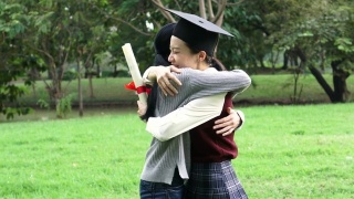 年轻的亚洲女毕业生在毕业典礼上拥抱她的朋友。国际多元化背景视频素材模板下载