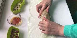 一名妇女用保鲜膜将拌有碎花生、葵花籽和蜂蜜的香肠包裹起来。自制的哈尔瓦做饭。