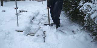 一位老人正在清理前院人行道上的积雪