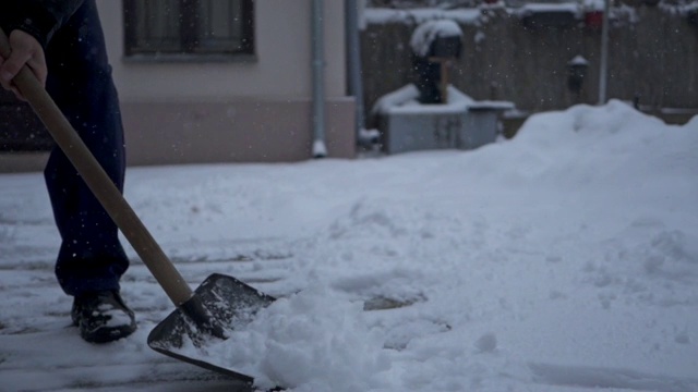 一个年长男子铲雪从他的后院的特写