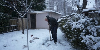 一个老人在前院用雪铲铲雪