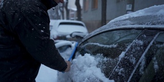 一位老人在暴风雪后清洗他的汽车