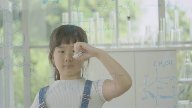 小亚洲学生女孩在透明的玻璃白板上写“科学”。人具有教育和科学的观念。