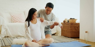 丈夫给怀孕的妻子背部和肩部按摩后，在家训练瑜伽或锻炼，健康和怀孕的概念