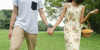 年轻的亚洲夫妇在大自然中享受春日，兴致勃勃地去野餐。人有生活方式、爱情观念。