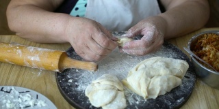 一位年长的妇女正在用烤卷心菜包饺子，乌克兰方式