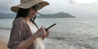 亚洲女游客在海滩上使用手机