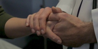 一个男医生用双手安慰一个女病人的特写
