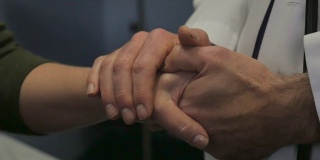 男医生用双手握住女病人的手安慰她
