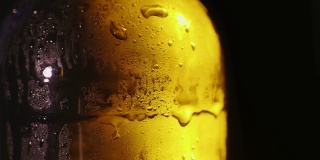 特写的一个玻璃瓶与凝结水滴。冷饮的概念。在黑色的背景上