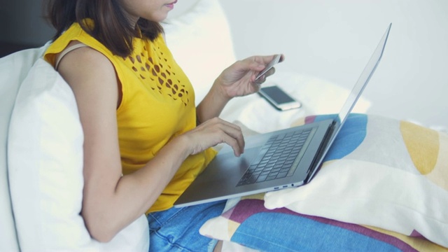 年轻女子在网上购物的笔记本电脑在家里。