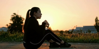 妇女在日落时间跑步后喝水