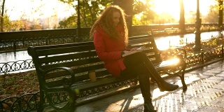 秋天晴朗的一天下午在公园里，小姐正在看书，女孩正坐在公园长椅上拿着她的包，秋天五颜六色的树叶覆盖人行道，放松在城市公园。概述