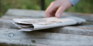 报纸放在一个木凳上。从木凳上取下报纸。
