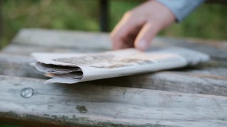 报纸放在一个木凳上。从木凳上取下报纸。视频素材模板下载