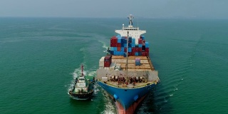 鸟瞰图或正面图拖船拖集装箱船从海港在海上行驶为物流进出口或运输。
