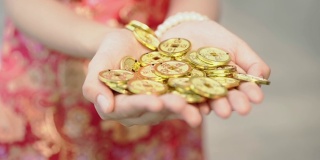 中国古代金币飘浮到身穿中国传统服饰的年轻女子手中，金字上寓意“钱是comingâ，过年快乐”的概念。