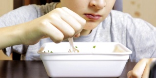 一个十几岁的白人男孩在家里吃中式快餐，用一次性容器装着方便面，他的老鼠很脏