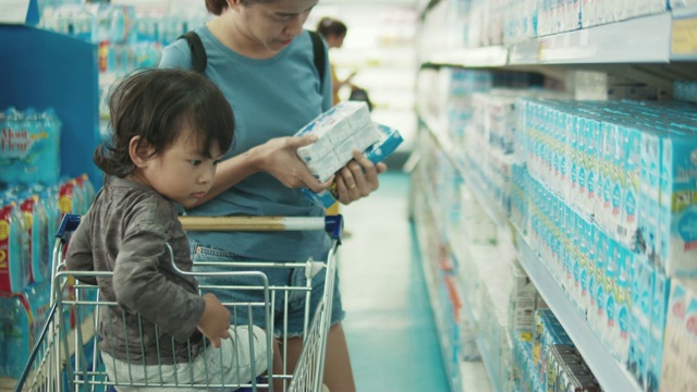 年轻迷人的妈妈和小孩在超市买食物。