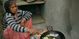 印度妇女在土坯炉上烹饪传统小吃。