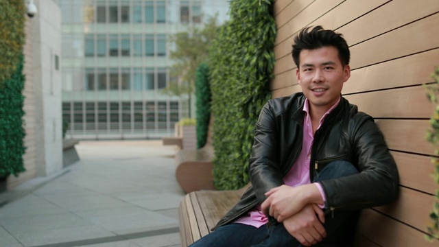 英俊的亚洲男人坐在长凳上