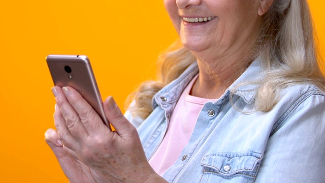上了年纪的女性在智能手机上打字，滚动手机应用，手机收费