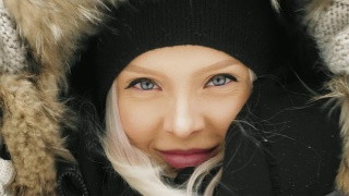 在大雪纷飞的冬日里，穿着舒适的皮大衣的漂亮年轻女人视频素材模板下载