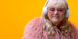 戴着白色耳机的酷奶奶随着音乐舞动，假装自己是dj，很有趣