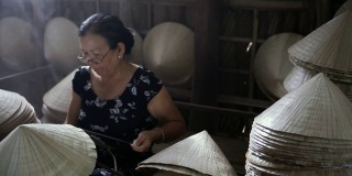 在越南Cantho省的Ap Thoi Phuoc村的老越南工匠制作传统越南帽子的4k镜头低光场景，传统艺术家的概念