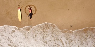 4K无人机拍摄的海岸线冲浪女子躺在海滩上