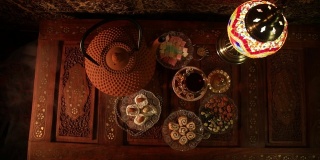 阿拉伯茶在玻璃和东方小吃在复古的木制表面。东方茶的概念。低灯光休息室内部地毯。空的空间。视图从上
