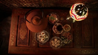 阿拉伯茶在玻璃和东方小吃在复古的木制表面。东方茶的概念。低灯光休息室内部地毯。空的空间。视图从上视频素材模板下载