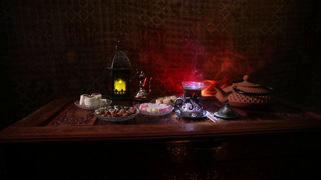 阿拉伯茶在玻璃和东方小吃在复古的木制表面。东方茶的概念。低灯光休息室内部地毯。空的空间。有选择性的重点。
