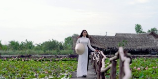 美丽的越南女人在大莲花湖的木桥上散步和呼吸新鲜空气的4k视频场景，越南，亚洲或东南亚的旅游概念