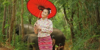 肖像迷人的亚洲妇女在传统东南亚服装看相机和微笑在自然的背景。