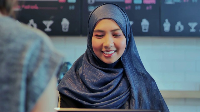 顾客在咖啡馆用信用卡支付他们的订单。伊斯兰妇女小企业主。穆斯林企业家的概念。阿拉伯青年