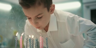 男孩在生日蛋糕上吹蜡烛。生日快乐男孩吹蜡烛火焰
