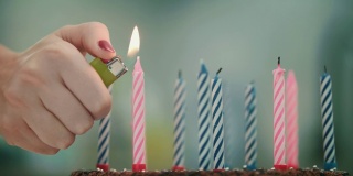 女性手在生日蛋糕上点燃蜡烛。生日快乐庆祝概念
