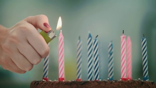女性手在生日蛋糕上点燃蜡烛。生日快乐庆祝概念视频素材模板下载