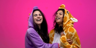 两个穿着独角兽和长颈鹿睡衣的女人笑着拥抱着，友谊