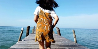 亚洲女孩在海边的木桥上跑步，慢镜头