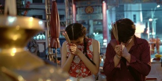 中国夫妇手持香烛在庙里祭拜。