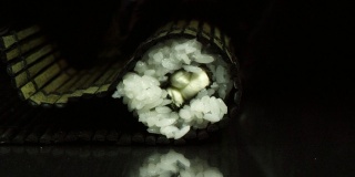 双手制作长寿司卷特写。米饭配鱼片。准备和切割传统寿司