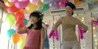 亚洲女儿喜欢在生日聚会上和爸爸妈妈一起跳舞。庆祝家庭幸福周年。节日与运动反应的概念。4 k决议。