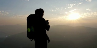 日落时分，徒步女子在山顶上用手机拍照，移动小车，慢动作