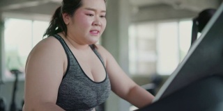 超重女性在跑步机上进行有氧运动在健身房里进行锻炼。