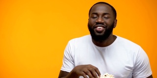 快乐的非裔美国人吃着爆米花大声笑着，喜剧表演