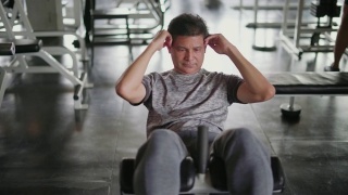 成熟的男人在健身房里坐着锻炼。视频素材模板下载