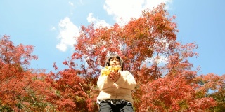 一个日本女孩在玩秋天的树叶